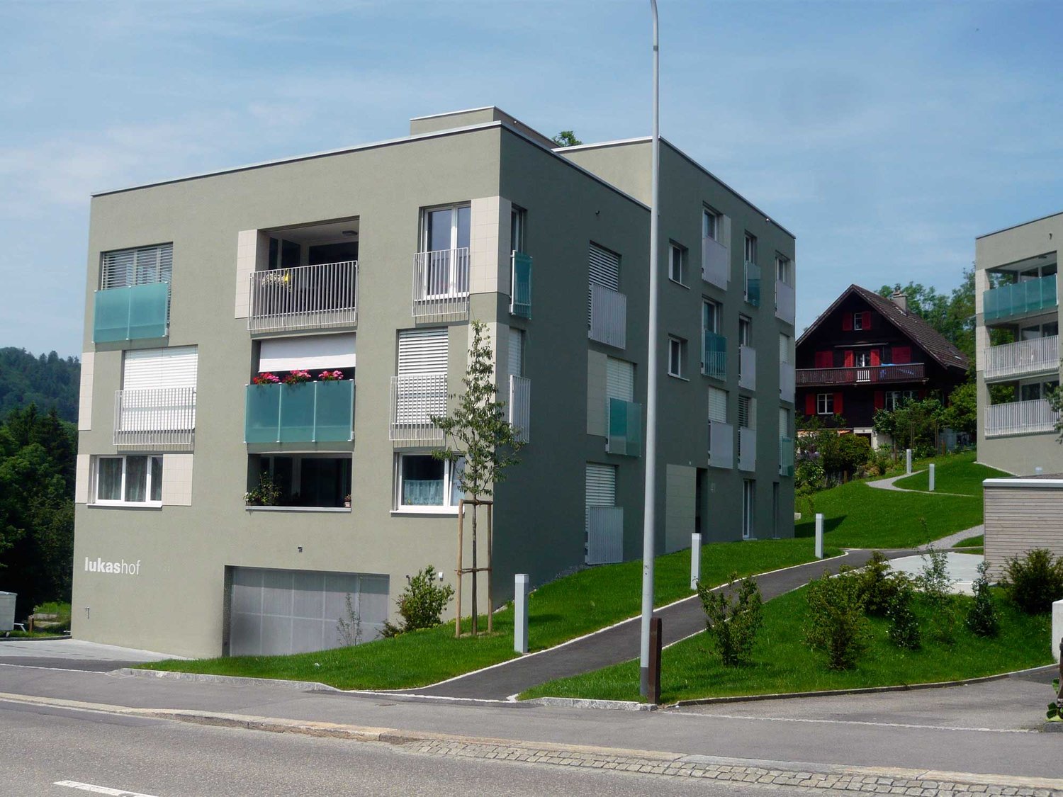 3-story apartment building with balconies, gray exterior, and landscaped grounds