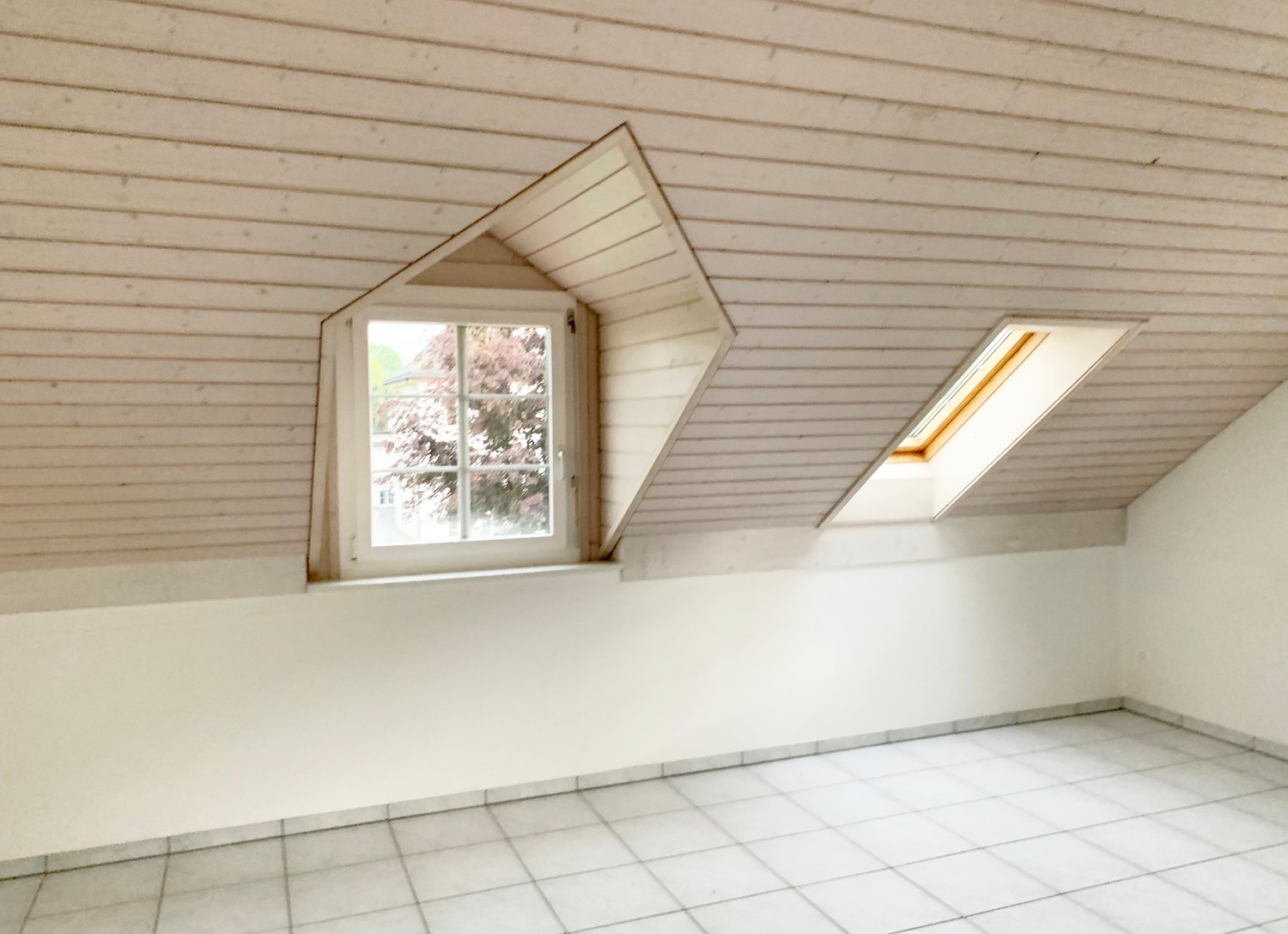 atop room with slanted ceilings, two windows, white tiles