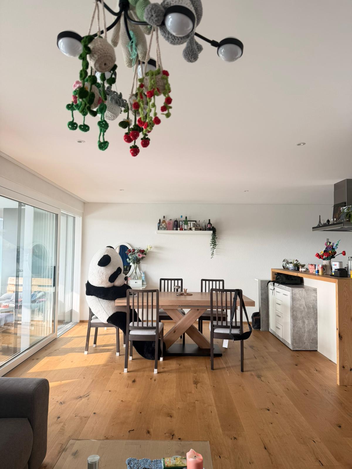 Dining room: wooden table and chairs, glass sliding doors, wooden floor, chandelier