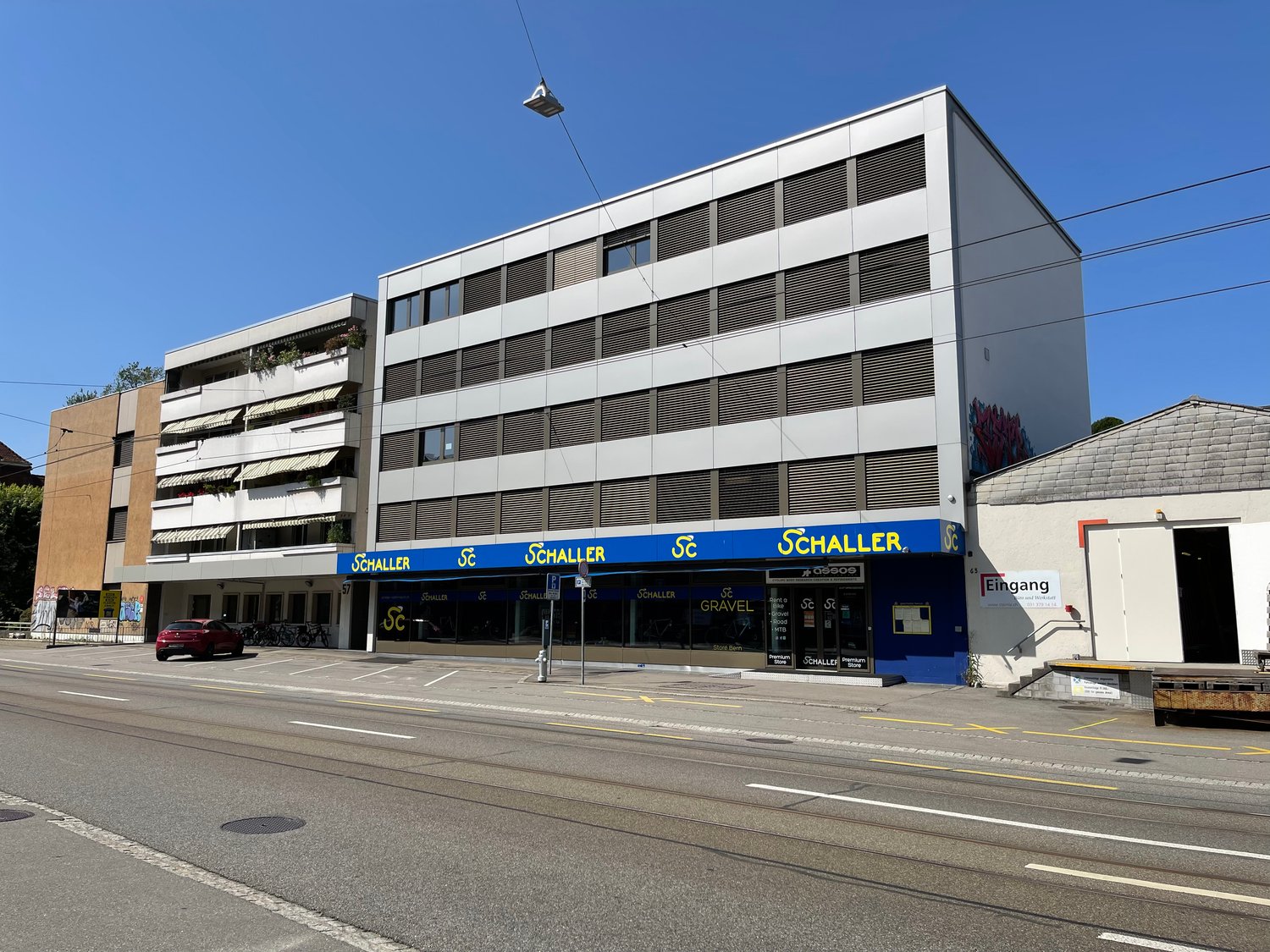 white multi-story building, blue storefront, street sign, entrance to store, fire hydrant, parked car