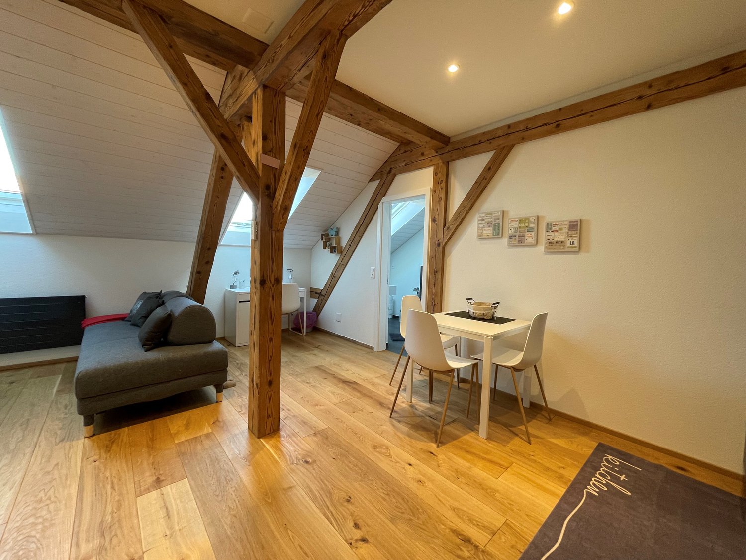 open floor plan, couch, desk, dining table, wooden beams, hardwood floors