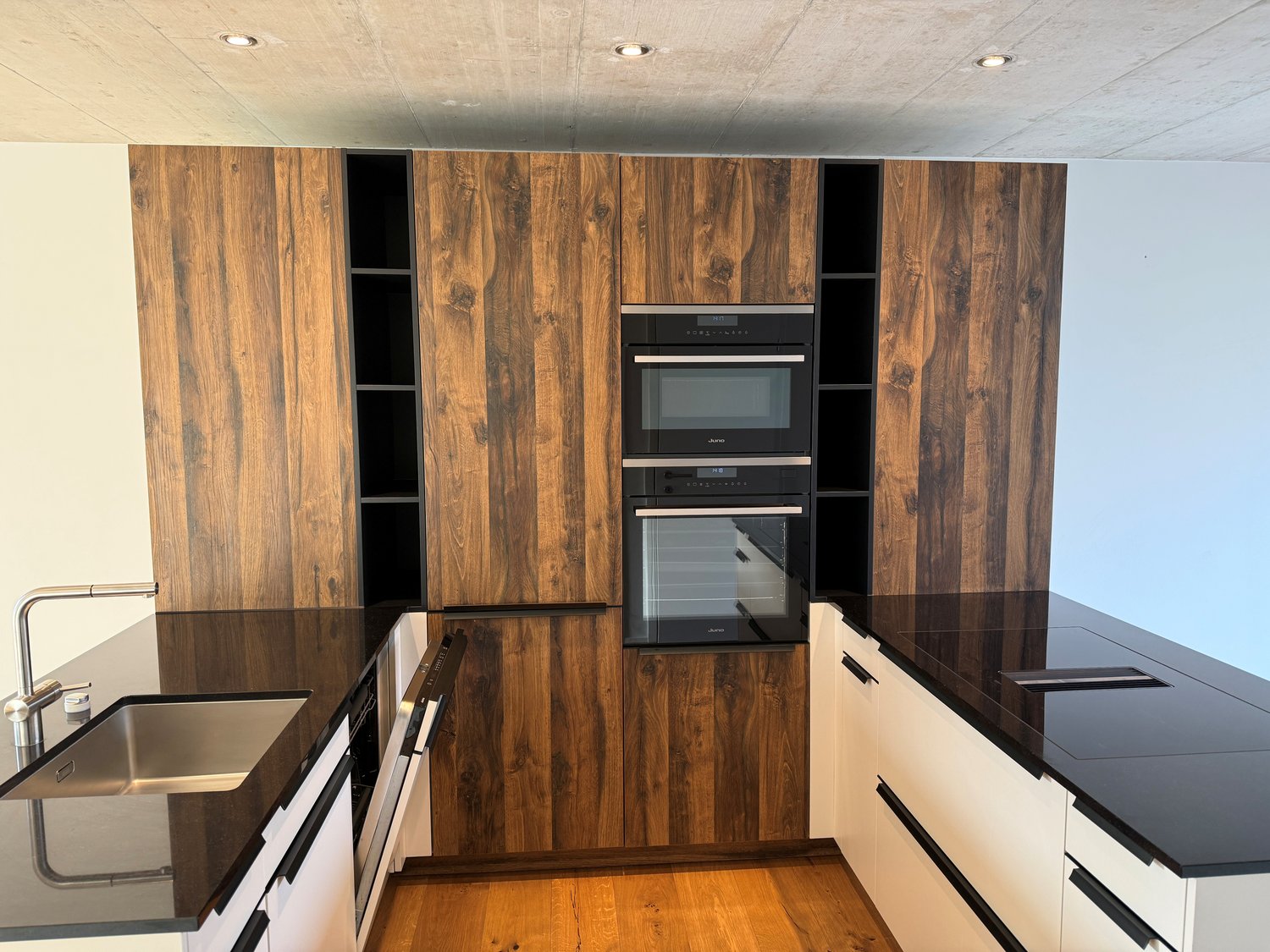 kitchen with wooden cabinets, black countertops, stainless steel sink, double oven
