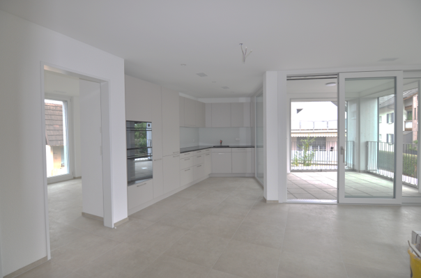 Open floor plan with kitchen, large windows, sliding glass doors leading to balcony