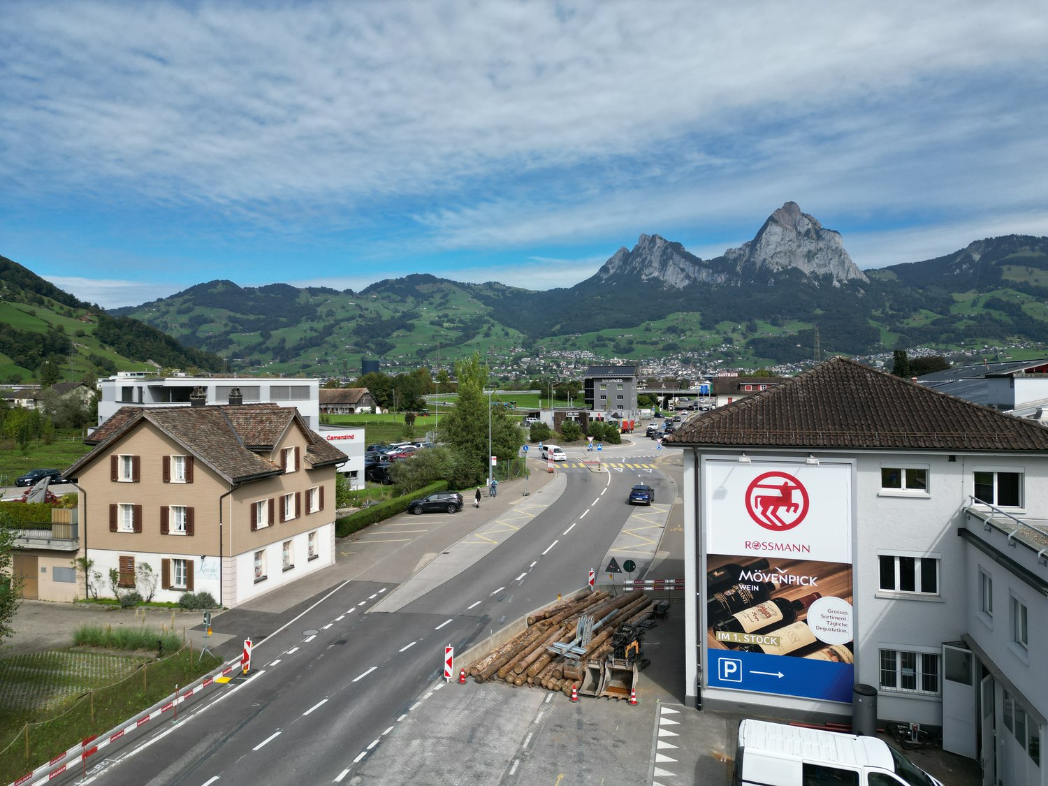 House with brown exterior and windows, parking lot, mountains in the background