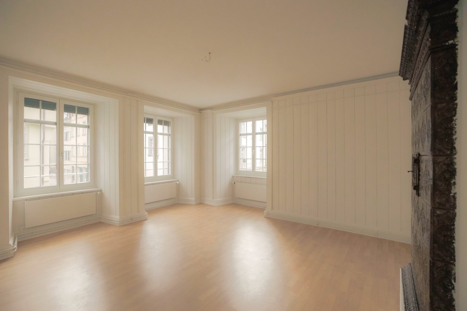 empty room, wooden floors, three windows, white walls, radiators