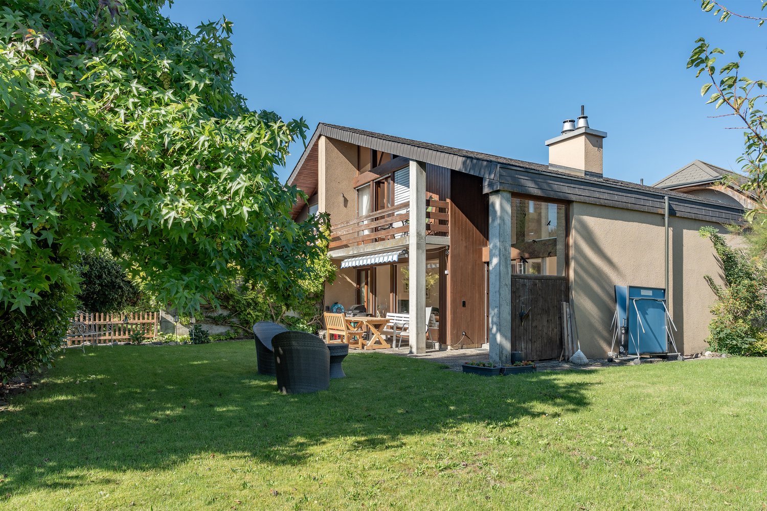 two story house, brown exterior, balcony, garage, backyard with table and chairs