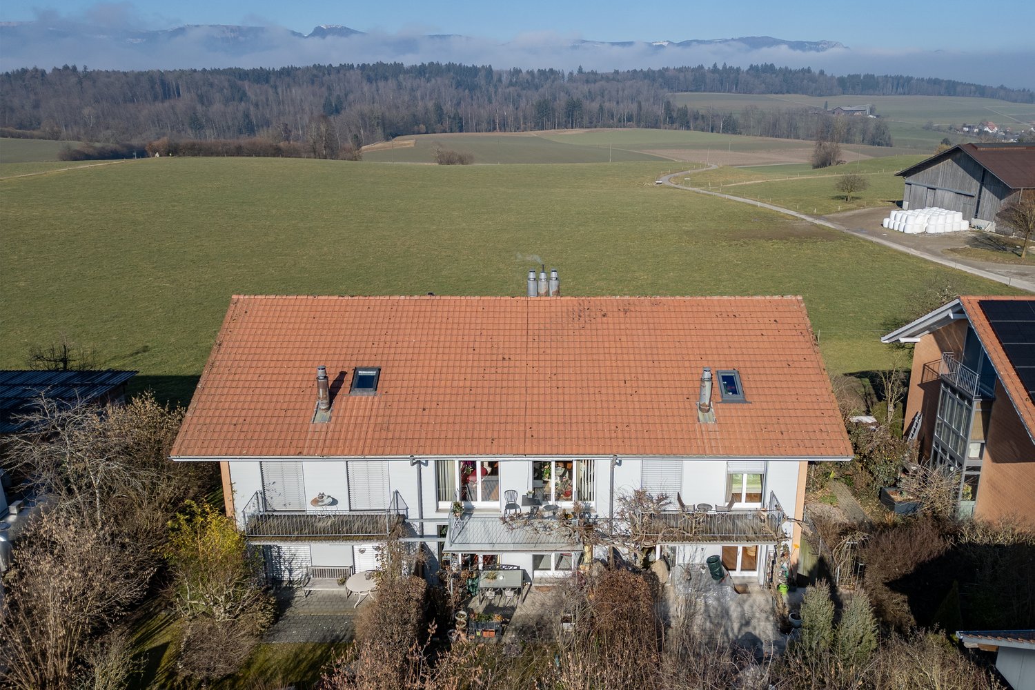2 story house, red roof, surrounded by fields, distant mountains