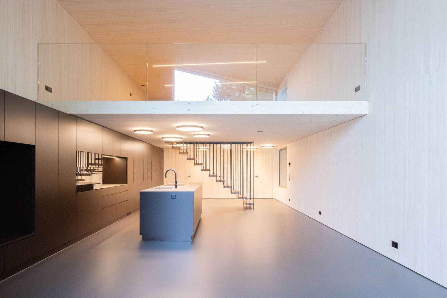 modern kitchen with island, glass railing, open staircase, wooden ceiling, white walls