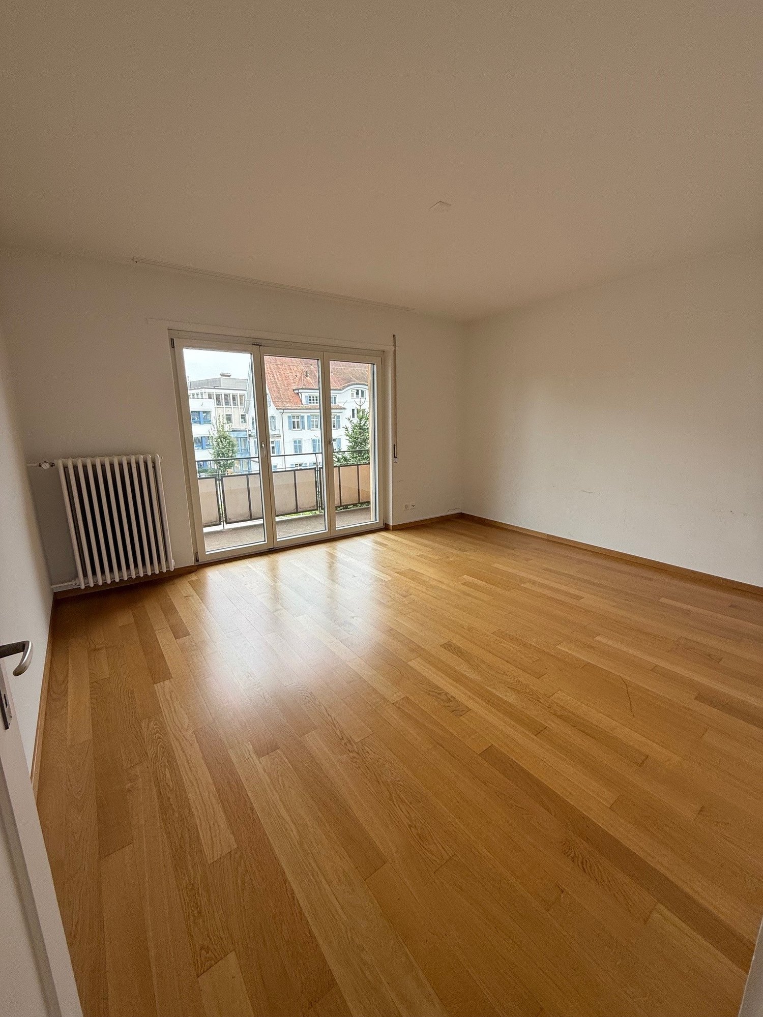 Empty room, hardwood floors, sliding glass doors, white walls, balcony