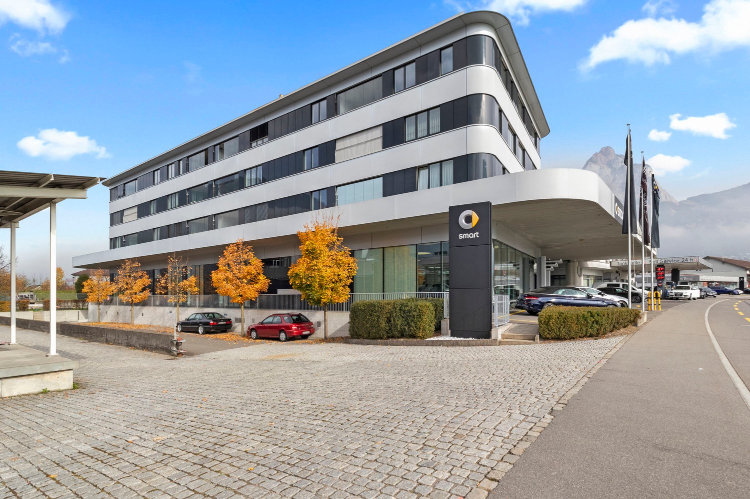 Modern building, black and white exterior, parking area, cars parked