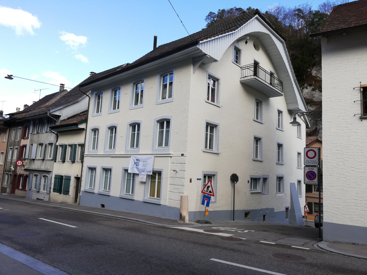 white building, many windows, balconies, brown roof, street in front