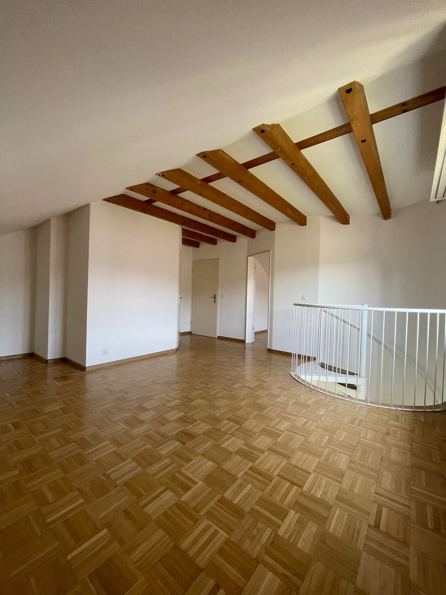 Open floor plan, wooden beams, wooden floor, staircase, empty room