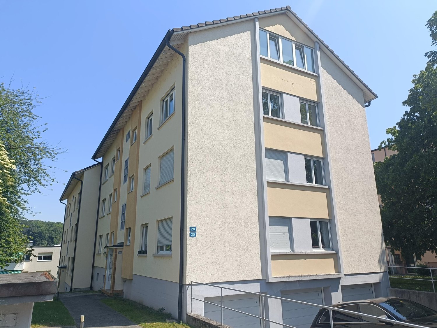 4 story building, beige and white exterior, multiple windows, entrance to underground garage