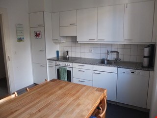 Spacious kitchen with white cabinets, stainless steel appliances, and a wooden dining table