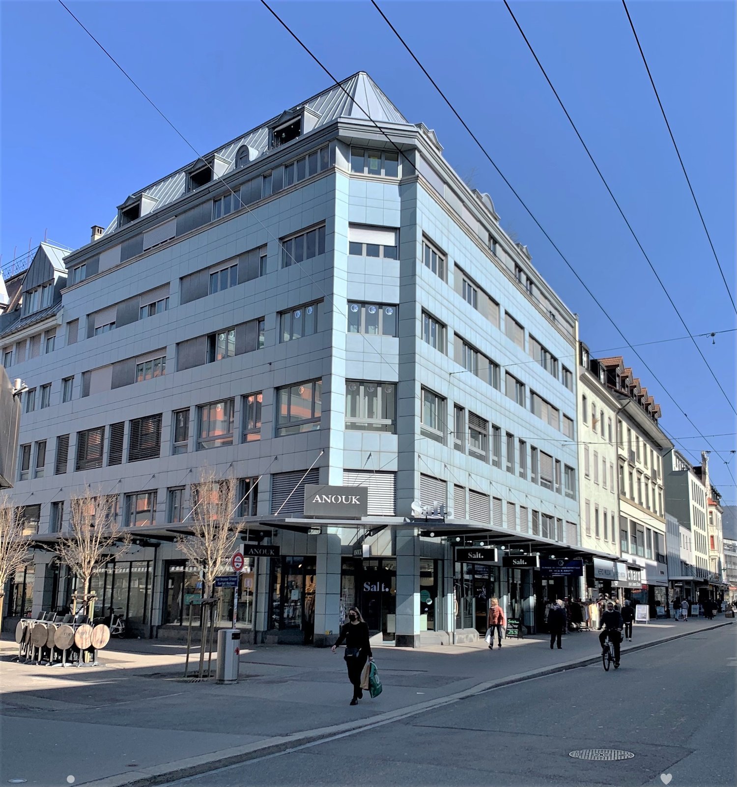 5 story building, gray facade, 30+ windows, storefronts at street level