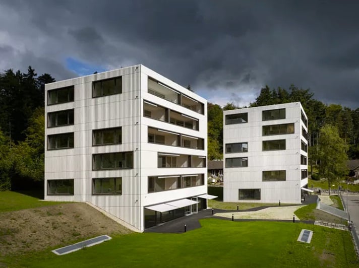 Modern building with many windows, 2 buildings, balcony, paved driveway