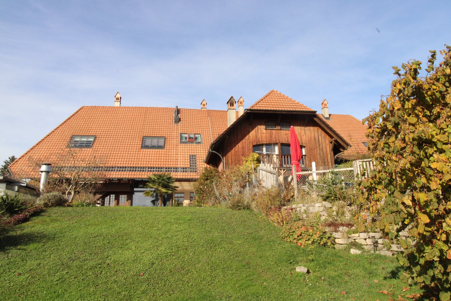 large house, red roof, wooden exterior, large front yard, fenced garden, multiple windows, multiple chimneys
