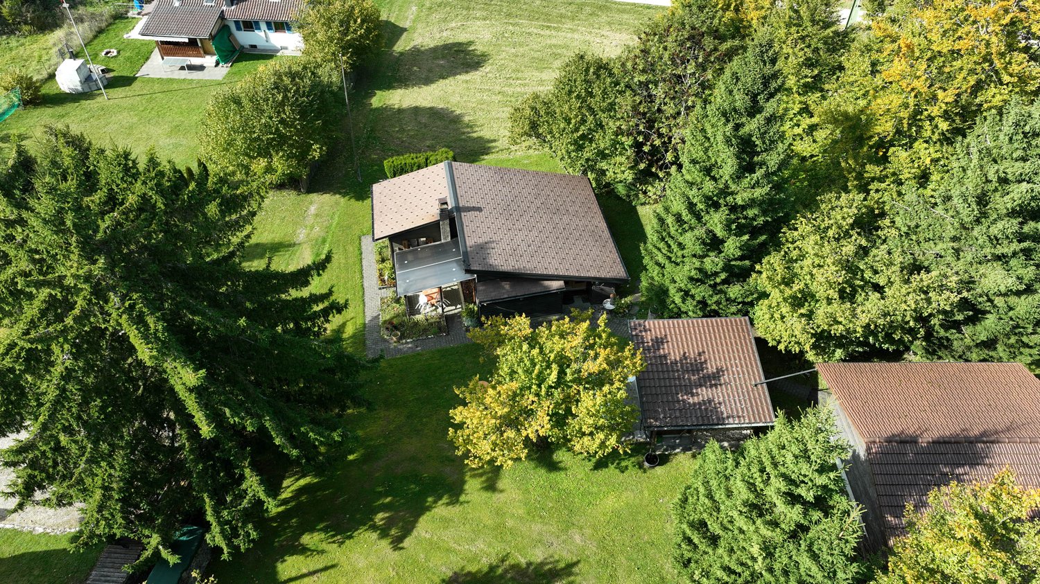 detached house with brown roof, large yard, surrounded by trees, patio