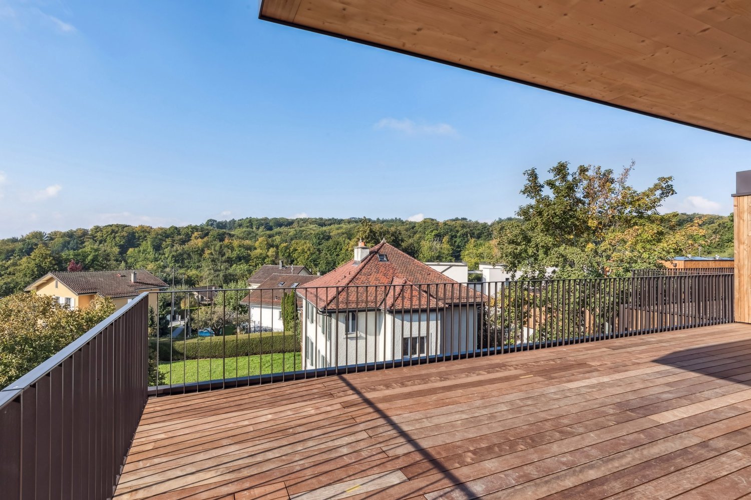 Wooden floor, metal railing, overlooking trees and houses