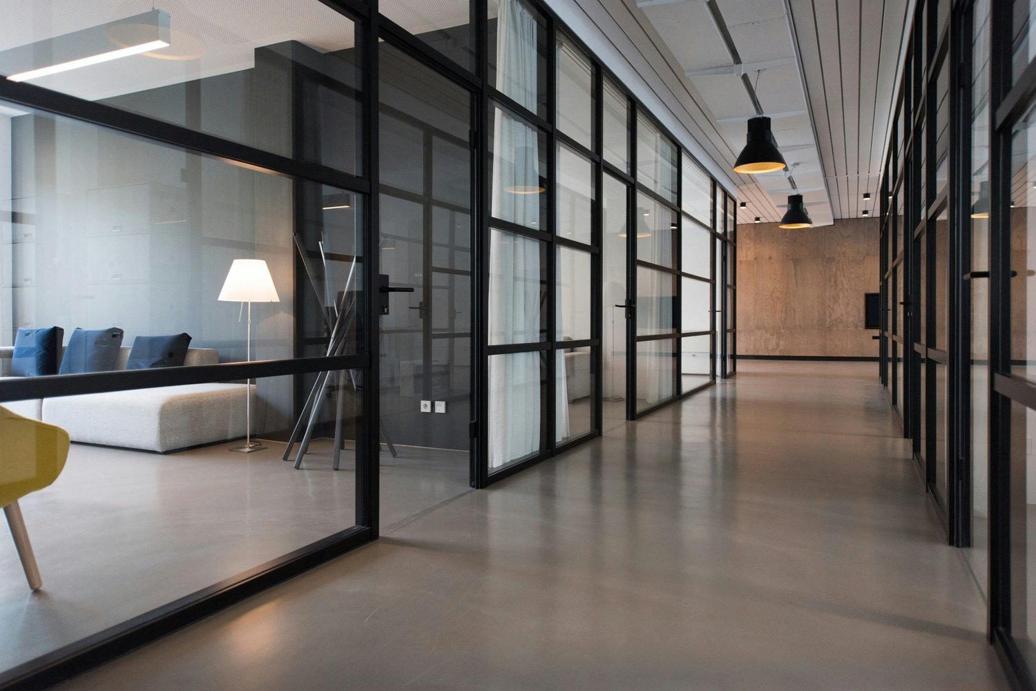 modern office space, glass walls, concrete floor, white walls, modern furniture, lamps