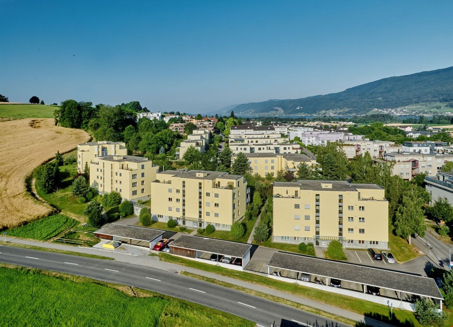 Aerial view of several multi-story buildings in a suburban area with parking lots and an entrance to the road