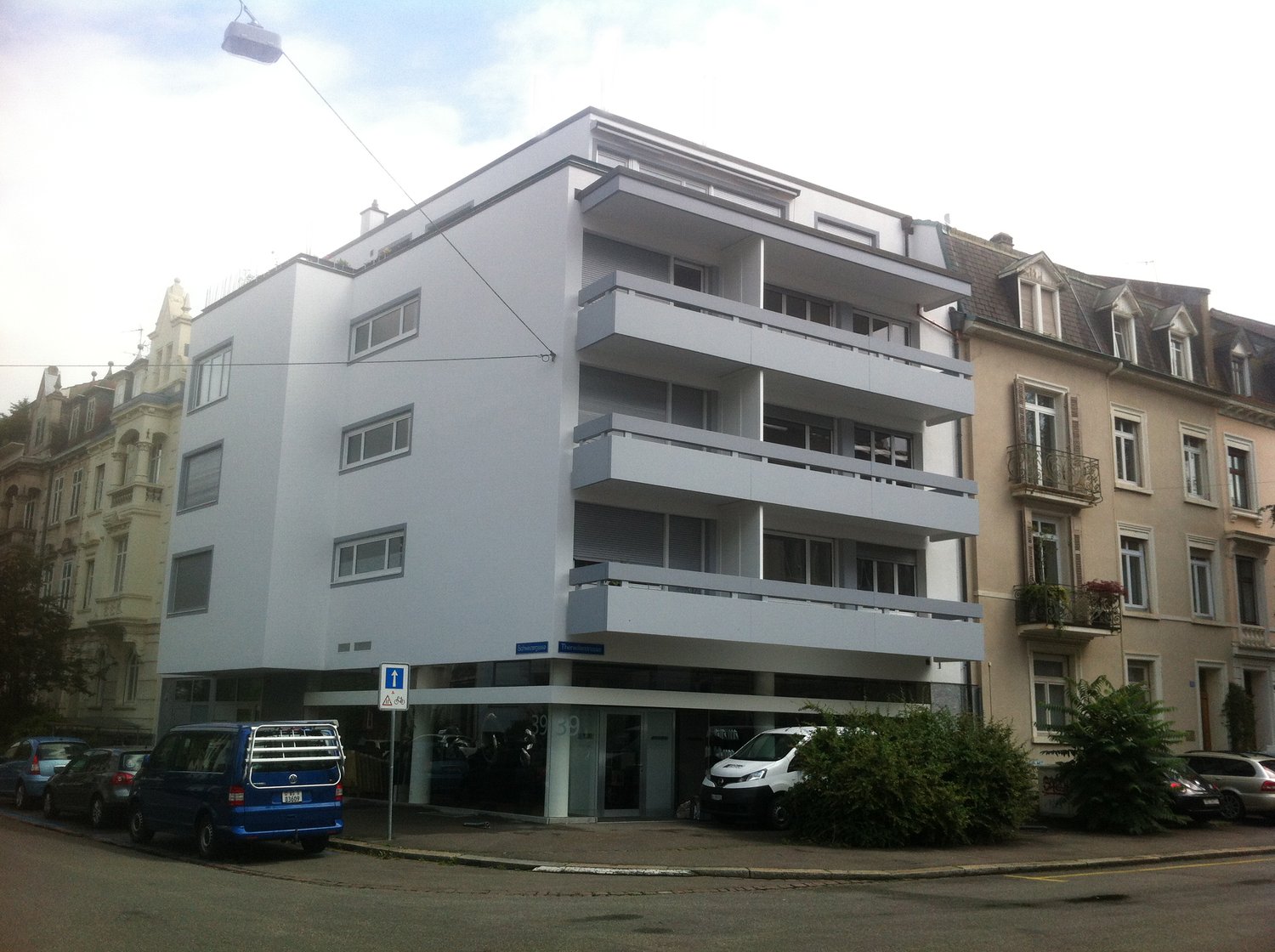 4 story building, white exterior, glass doors, several balconies