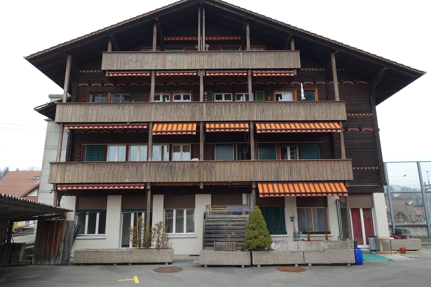 3-story wooden chalet-style building with balconies, decorative wooden trim, and awnings