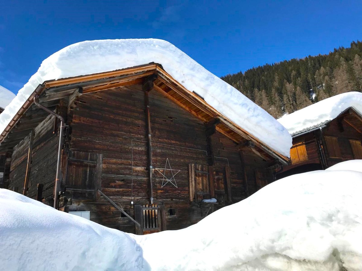 Traditional wooden house, raised ground floor, snowy roof, wooden beams, star decoration