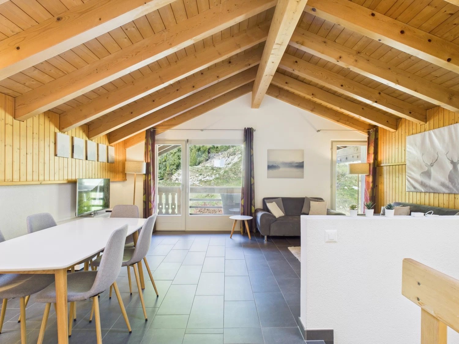 open plan living and dining area, wooden beams, tiled floor, large windows with balcony