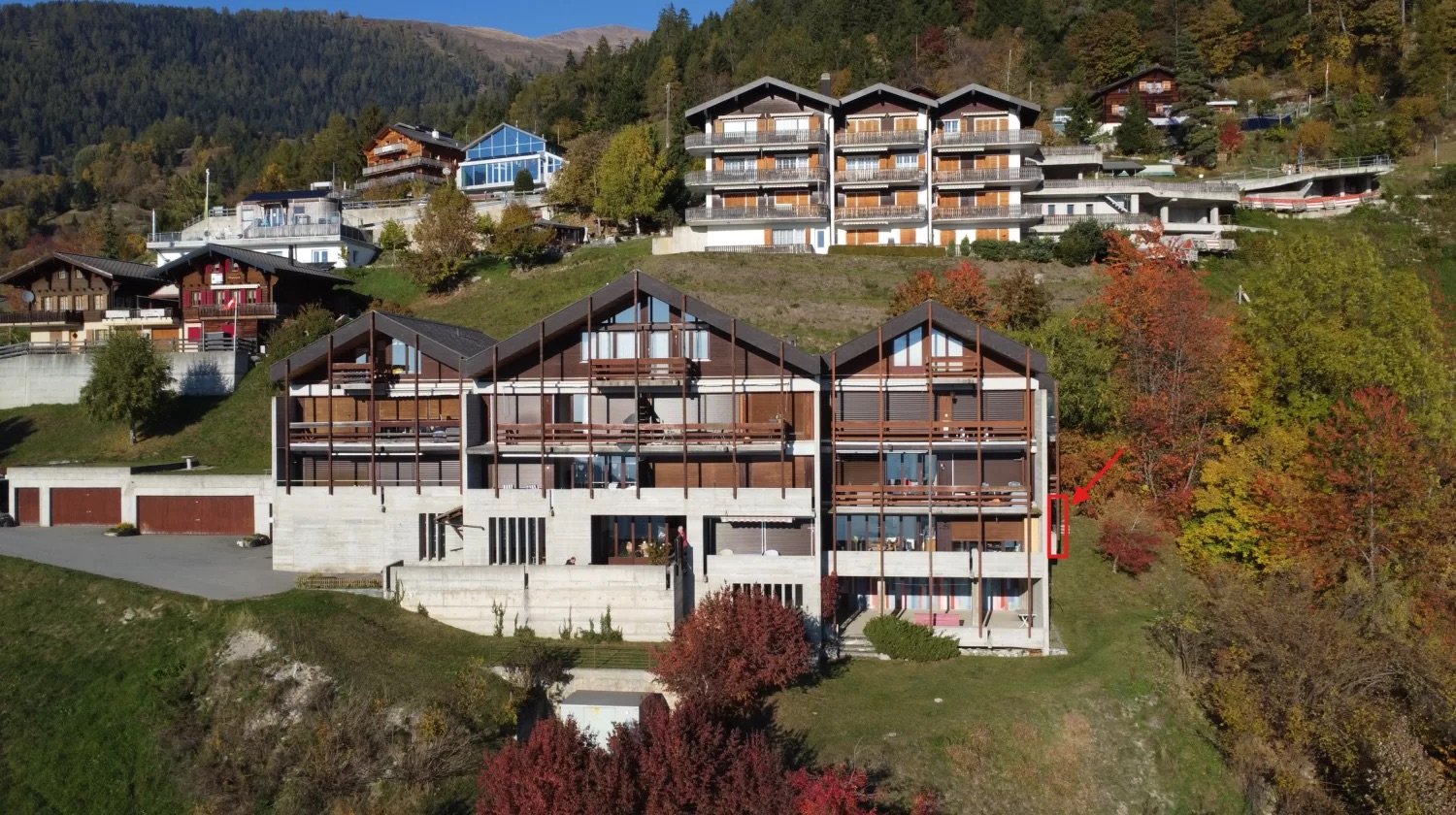 Apartment building on hill, with multiple balconies, underground parking