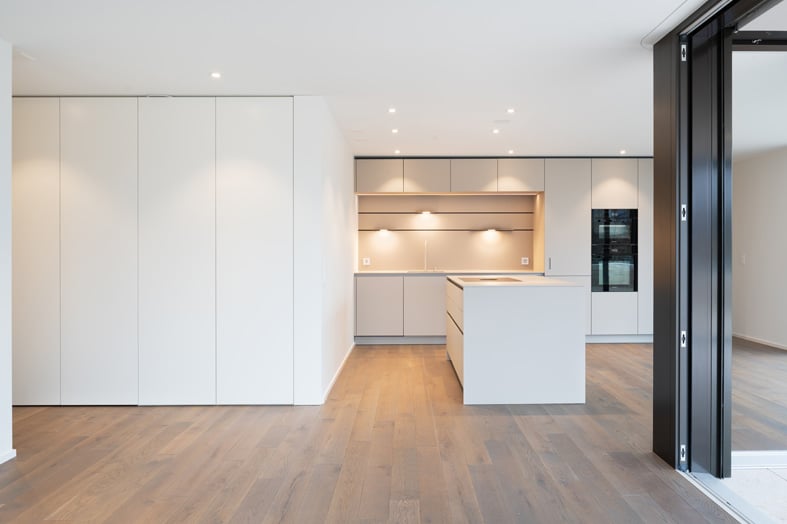 an open kitchen, central island, built-in cabinets, wooden floor, white walls, modern fixtures, an oven