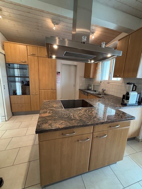 modern kitchen with granite countertop, wooden cabinets, built-in oven, electric range, island with sink, dishwasher, and faucet