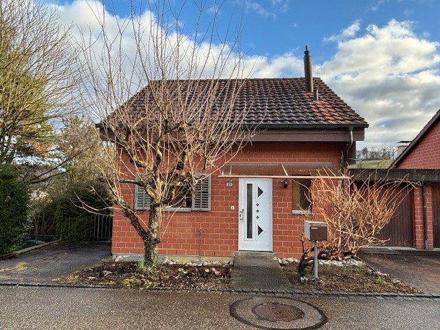 red brick small house, white door, windows with white shutters, chimney