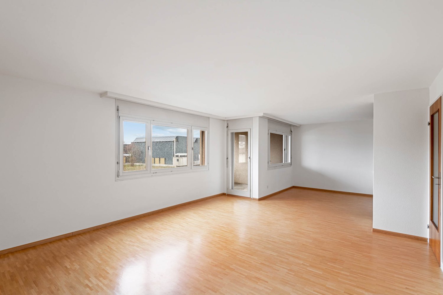 Empty room with white walls, wooden floor, large window, glass door