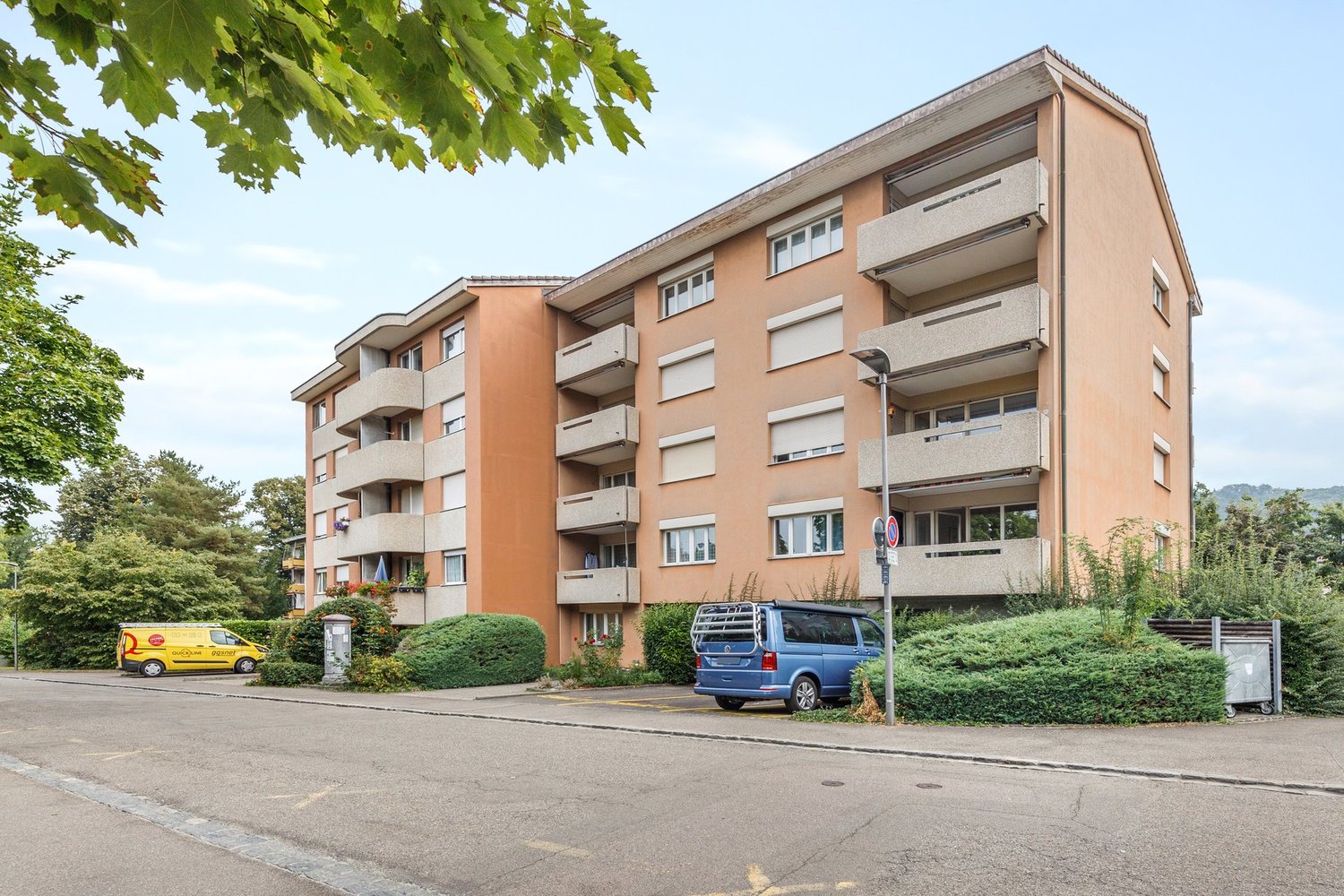 4 story apartment building, balconies, cars parked in front