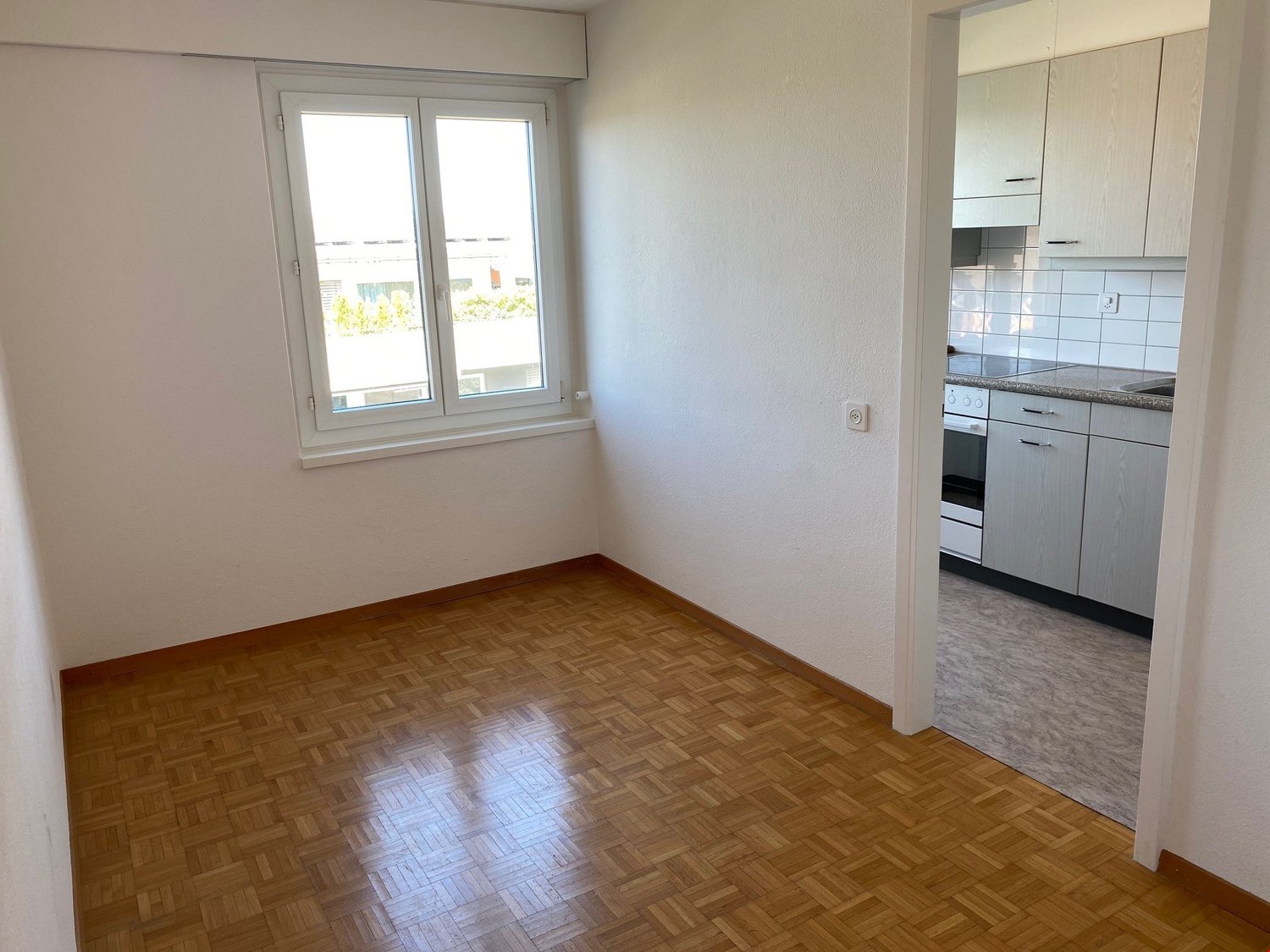 empty room, parquet floor, white walls, window, doorway leading to kitchen