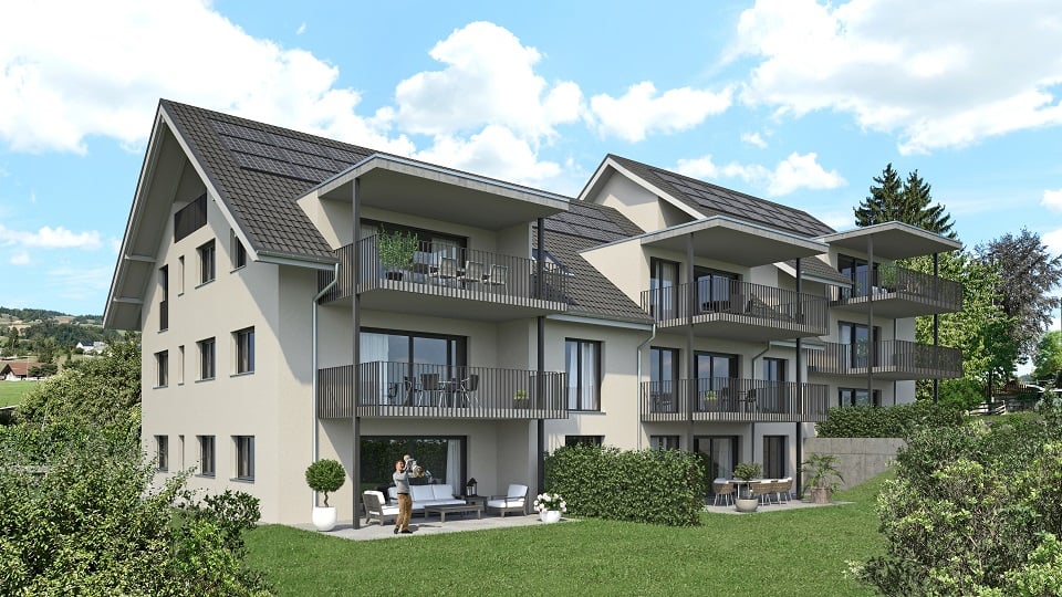 3-story apartment building with gray exterior, black roof tiles, and balconies on each unit. The building is surrounded by a grassy area with trees.