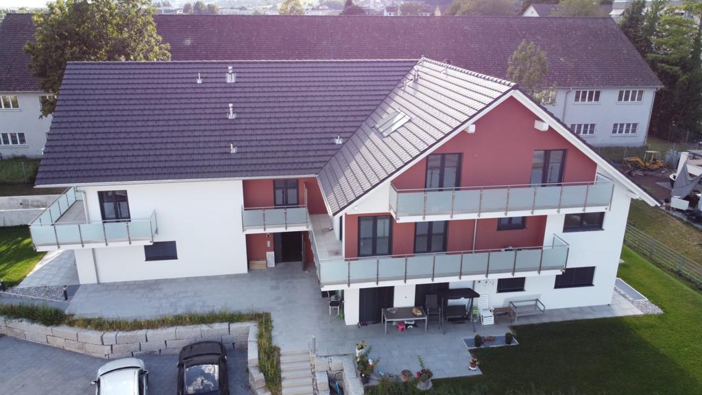 2 story house, red and white, 2 balconies, 2 cars parked, garden, patio