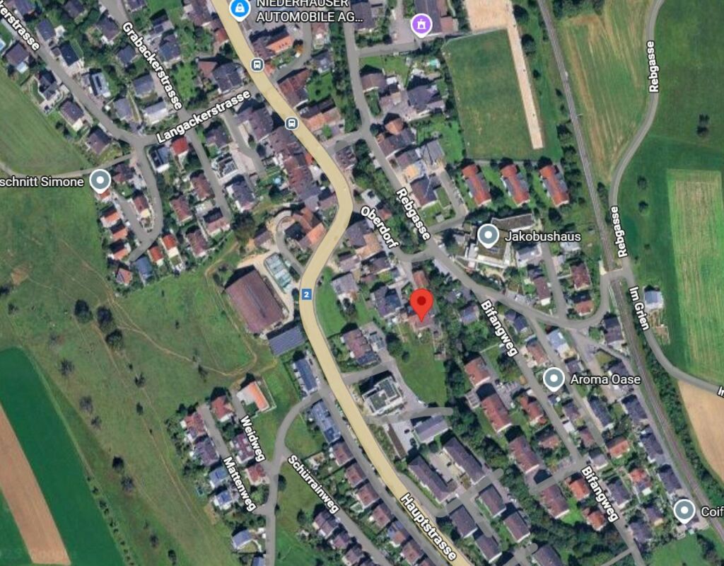 Aerial view of a neighborhood with residential buildings, roads, and green fields.