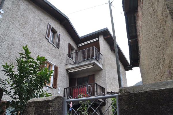 Two story building, concrete exterior, white windows, balcony, small front garden