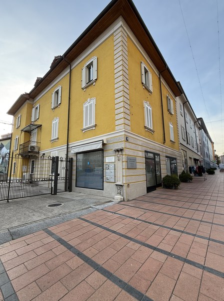 Yellow building, multiple windows, brick floor, black iron gate, balcony