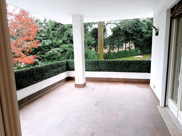 empty balcony with tiled floor and column, plants, trees in the garden