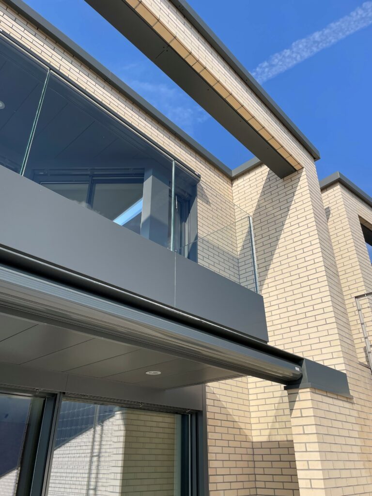 Balcony with glass railing, brick wall, glass windows