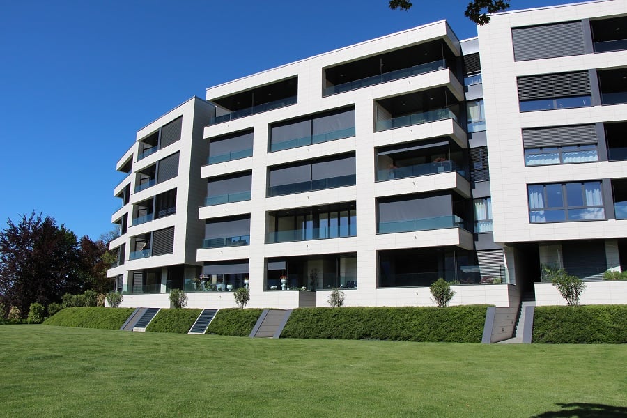 Modern apartment building, white exterior, large windows, balconies, landscaped lawn