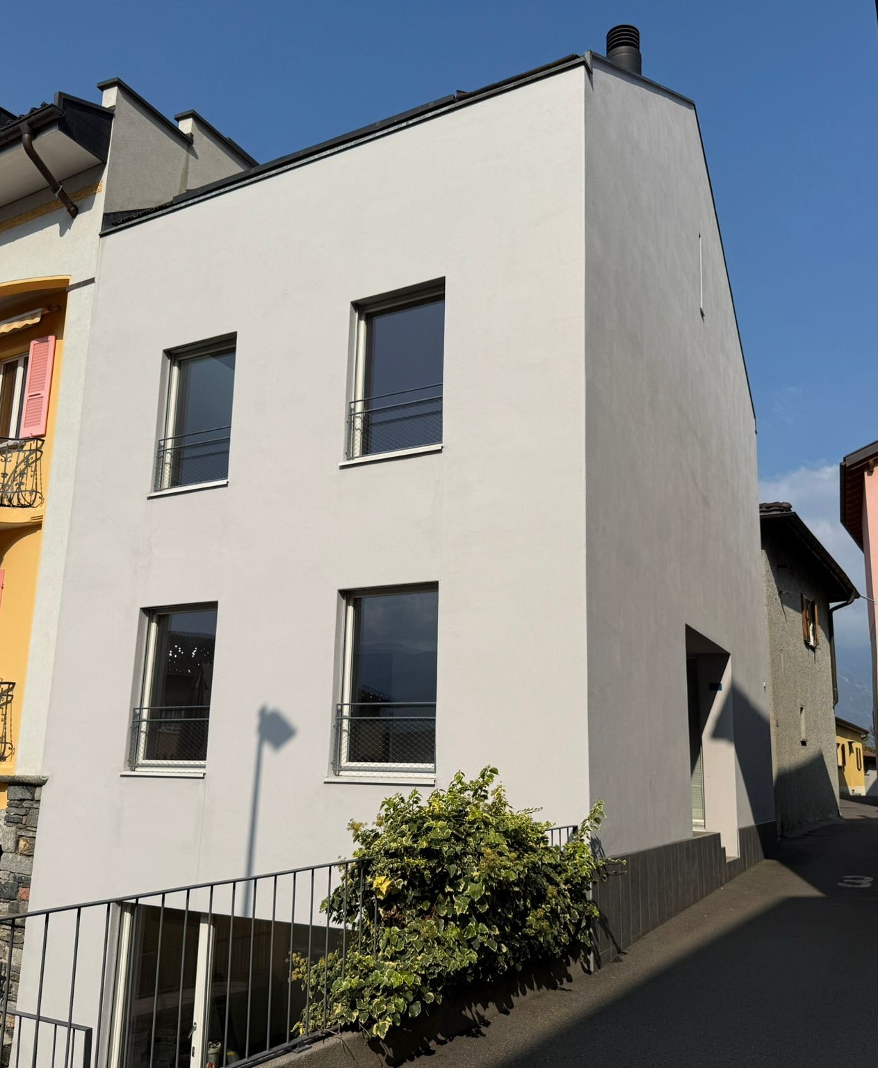 White painted house, 3 floors, 4 windows, balcony on second floor