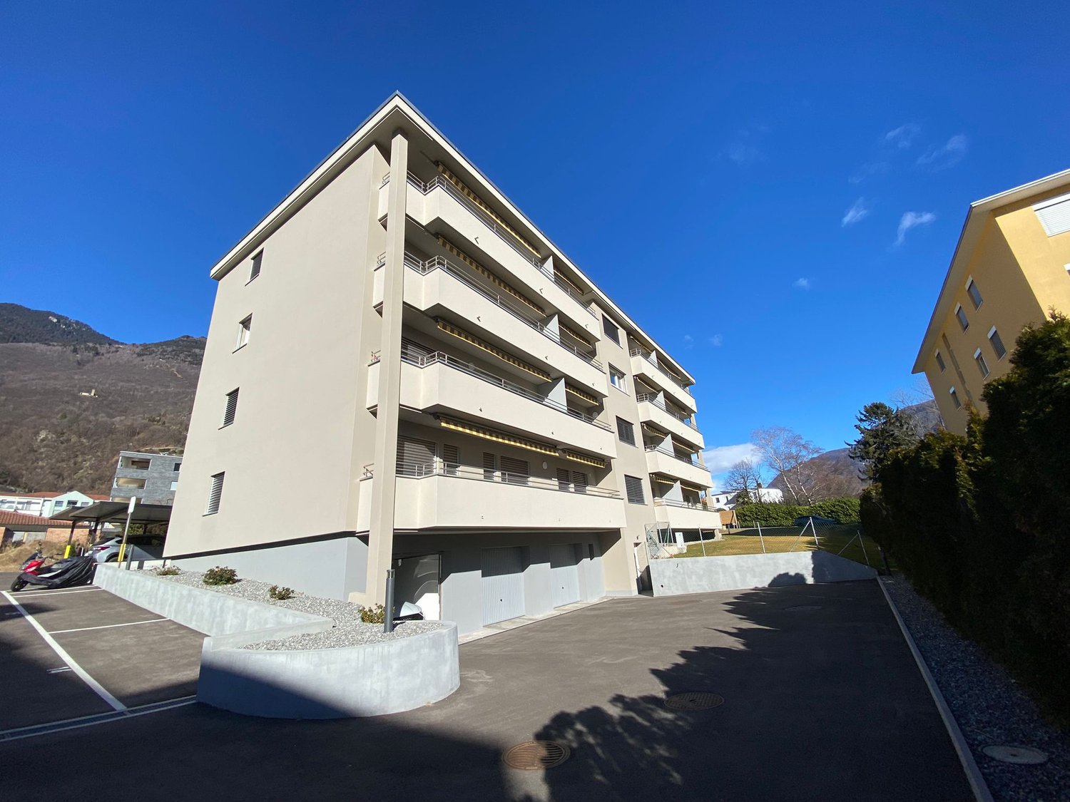 residential building, multiple balconies, parking lot, garages