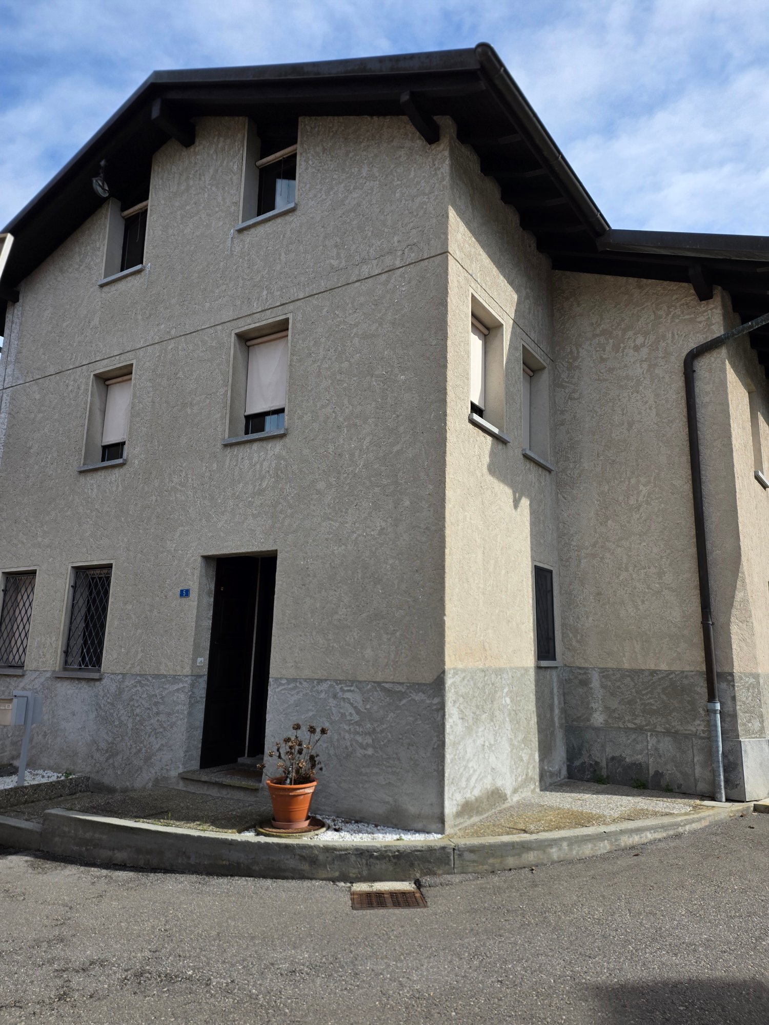 2 story house, gray exterior, multiple windows, entrance with steps, small potted plant
