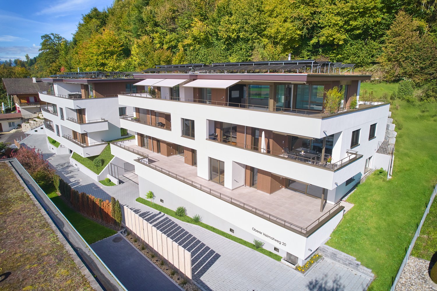 Modern 2 story apartment building, white and brown exterior, multiple balconies, solar panels