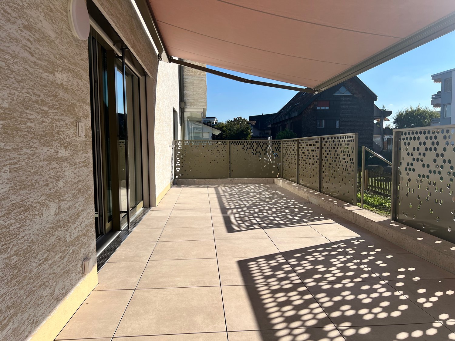 covered balcony with tiled floor, metal fence, and retractable awning