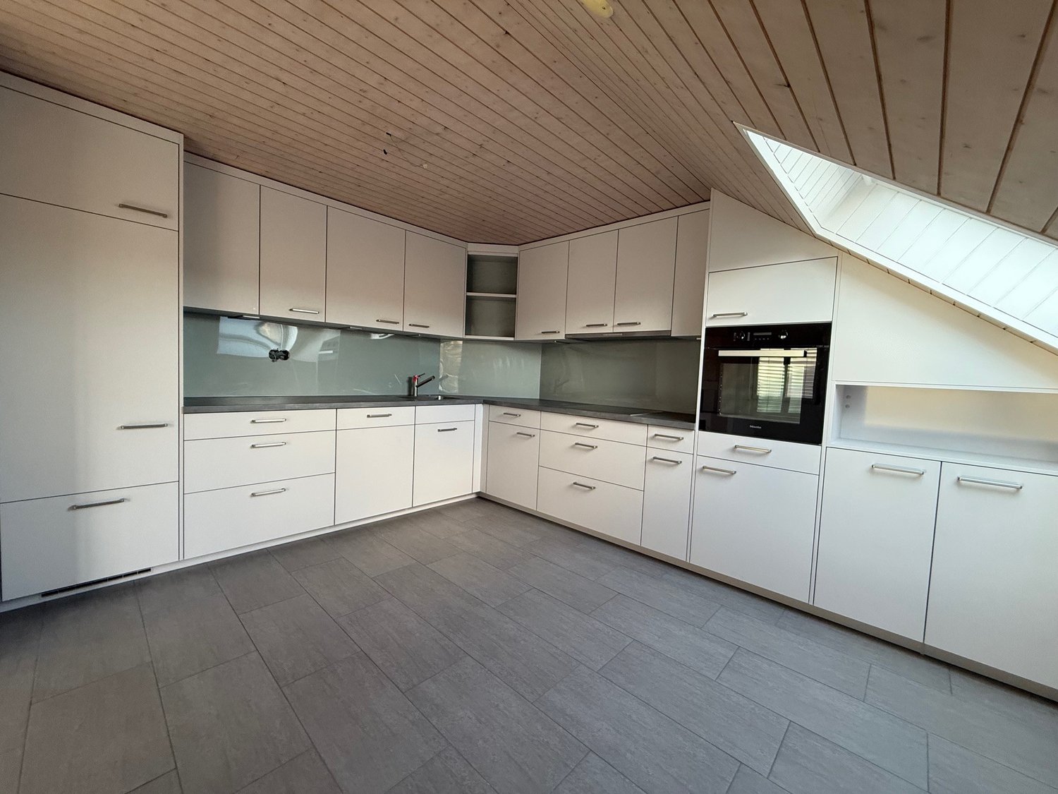 modern kitchen with built-in appliances, glass front cabinets, gray flooring, wooden ceiling